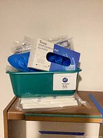 Green tub holding PVC disposable gloves box, pill organizers, white plastic sticks