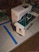 Boxed Memorex Universal Speaker stacked on boxed Logitech AudioStation Express