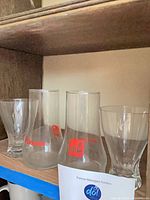 Front view of all four glasses on shelf showing logos and crystal design