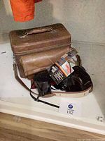 Camera gear grouped with brown carrying case