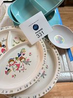 Overview showing two blue divided dishes, two white kids sectional plates with alphabet design, and Dumbo bowl