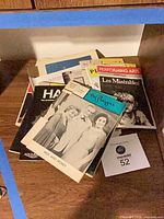Stack of theatre playbills on shelf showing titles Les Miserables, Hair and others