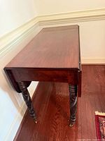 Side view of mahogany drop-leaf table, barley twist legs, brass casters