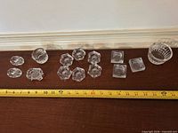 All sixteen clear pressed glass pieces with measuring tape for scale