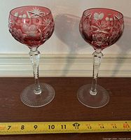 Front view showing both cranberry cut-to-clear wine goblets with measuring tape indicating 10 inch height