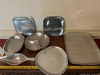 all seven aluminum serveware pieces on table with tape measure