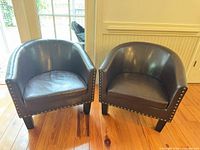 Front view of both matching dark brown faux leather club chairs