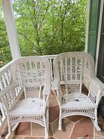 Pair of white wicker rocking chairs on porch