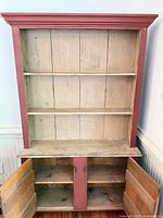 Front view showing full hutch with open cabinet doors, red exterior, natural pine interior