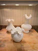 Front view of three white milk glass vases showing textures and ruffled rims