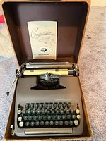 Typewriter in open carrying case with instruction booklet displayed