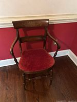 Front view of Victorian wooden armchair with red seat cushion