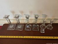 All six candlesticks lined up with tape measure for scale