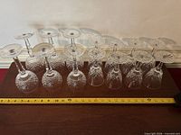 All 14 wine glasses upside-down showing bowls, stems and starburst bases beside measuring tape