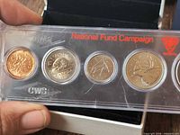 Front view showing four coins and two empty spots in plastic holder