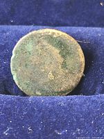 Heavily worn coin in display slot showing obverse side