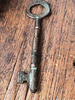 Full view of key on wood surface showing size and patina