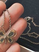 Necklace on hand showing butterfly pendant detail and chain