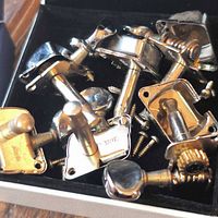 Assorted metal guitar tuning machine heads and screws in box