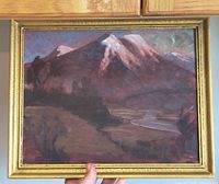Front view of framed mountain landscape painting held by hand