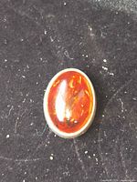 Front view of oval amber cabochon in silver bezel
