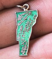 Front of green enamel Vermont state charm with raised lettering