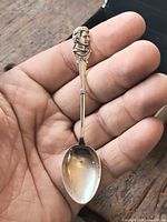 Front of sterling silver spoon in hand showing bust detail and bowl
