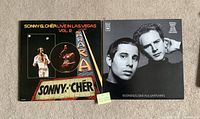 Front covers of both vinyl LP records laying side by side on carpet; sticky note for scale
