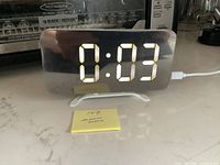 Front view of LED alarm clock on stand displaying time