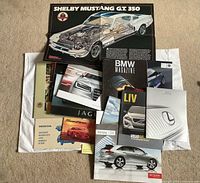 Top-down view of stack showing Shelby Mustang poster, multiple branded brochures