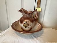 Pitcher and bowl front view showing floral motif and glaze