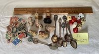 Group shot of all items including spoons, figurines, stamps, dice with ruler for scale
