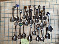 All 21 souvenir spoons laid out on grid surface