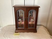 Front view of closed wooden jewelry cabinet with stained-glass doors