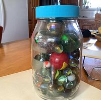 Front view of clear jar showing assorted marbles of various sizes and colours