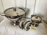 Large and small stainless steel lidded bowls with three of the clip-on plates in front