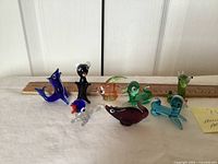 All eight miniature glass animals lined in front of ruler for scale