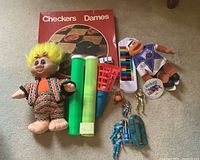 Full lot overview showing board game, troll, piano, Pogs tubes, catch basket, Thunderbirds items and plush