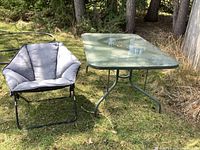 Glass patio table and grey bucket chair outdoors