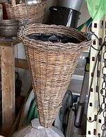 Full view of wicker cone planter hanging in storage area
