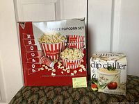 Retail box of 7-piece popcorn set beside boxed dip chiller