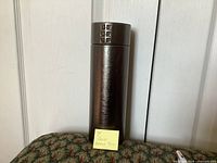 Closed cylindrical case with sticky note identifying set