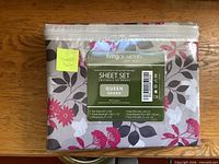 Front of sealed LivingQuarters queen sheet set package showing brand, size, contents, floral pattern