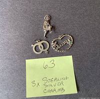 Overview of three sterling silver charms on grey background