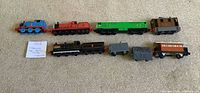 Side profile of all eight Thomas & Friends die-cast train pieces laid out in one row