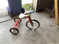 Side view of red and white tricycle showing frame, seat, wheels