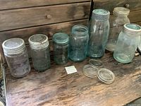 Lineup of seven jars with lids on wooden surface