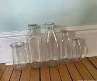 Five clear glass bottles lined up showing relative sizes