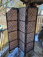 Full view of three-panel metal and rattan folding divider standing partially open on deck