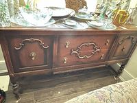 Front view of wood buffet showing drawers, doors, legs, hardware